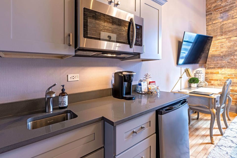 Gray shaker cabinets, granite counters, Keurig, microwave, and mini fridge. A complete kitchenette that keeps the aesthetic.