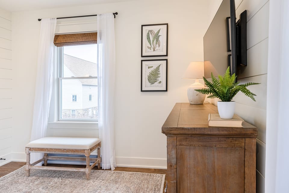 A well-appointed bedroom with a sitting bench, natural light, and everything thoughtfully in its place.