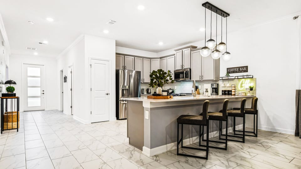 Bright, modern kitchen with island seating, pendant lighting, and coffee station.