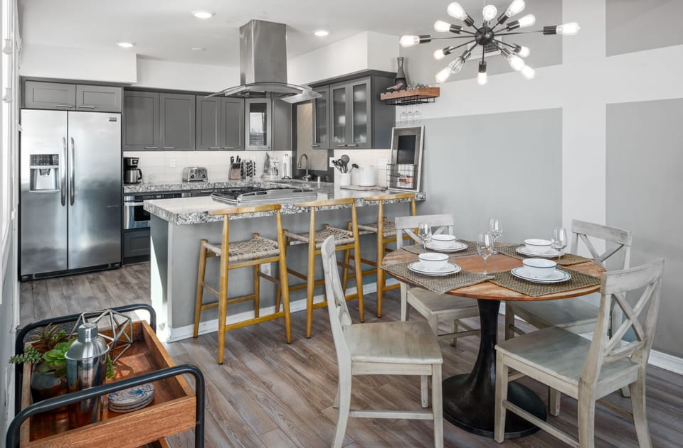 This open-plan kitchen boasts high-end appliances and a casual dining area, complete with a breakfast bar, stools, and a table with chairs.