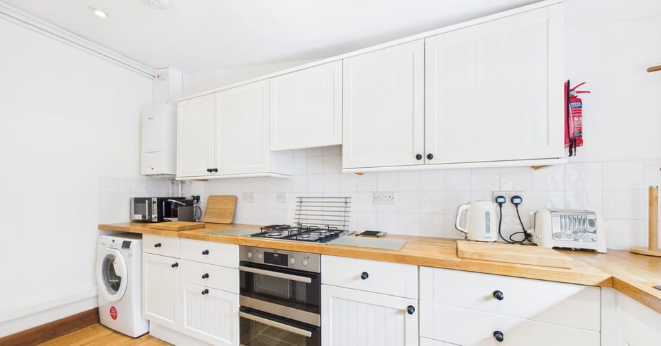 Well-equipped kitchen with washing machine, oven, microwave, kettle, toaster & coffee machine.