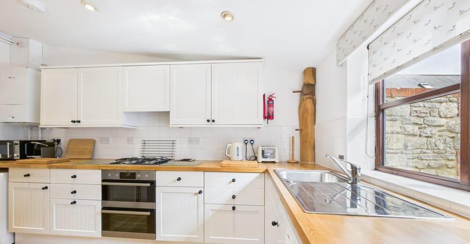 Detail of appliances at The Cote kitchen including oven, microwave, fridge/freezer, washing machine and kettle.