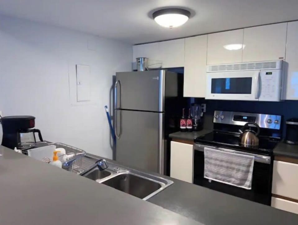 Fully equipped kitchen with appliances, utensils, dishes, tea/coffee supplies.