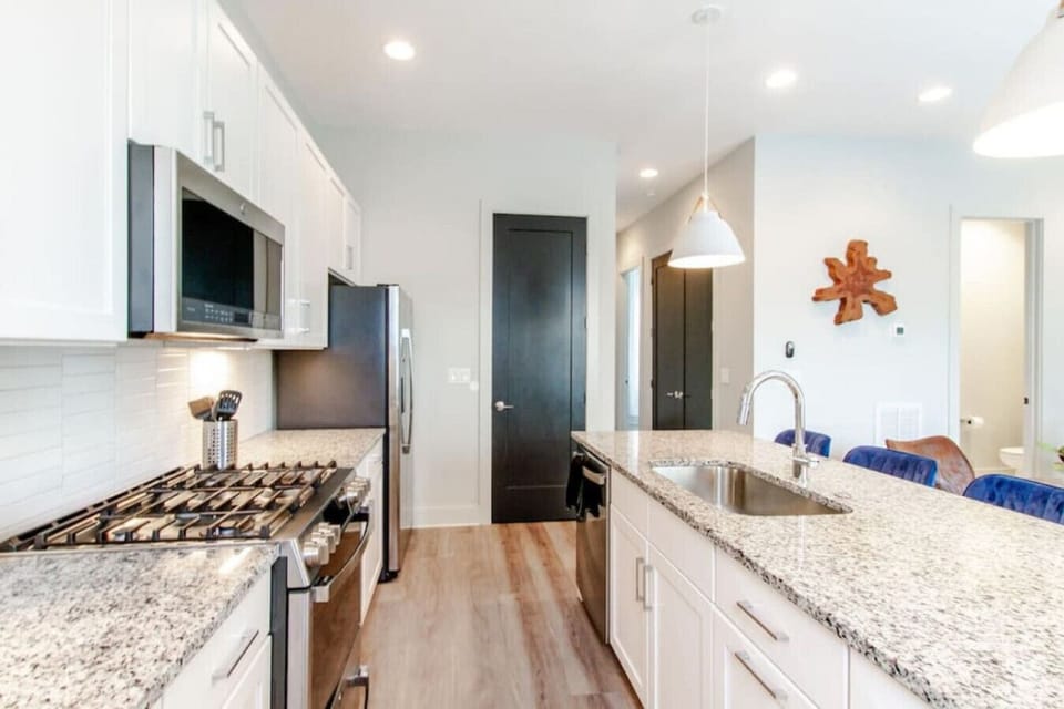 The kitchen features stainless appliances, dark cabinetry, and a full dining island to gather around.