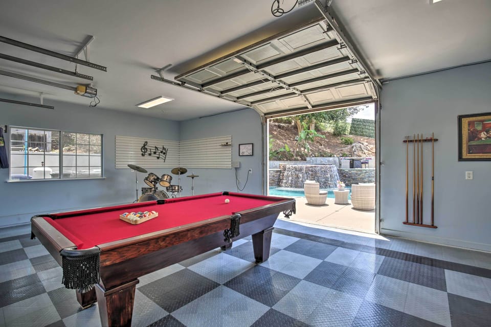 Garage game room with red pool table, retro flooring, and open view to pool deck