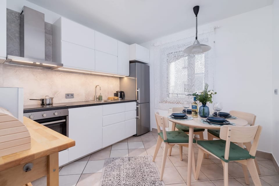 A kitchen with wooden cabinetry, modern appliances, and a small dining area.
