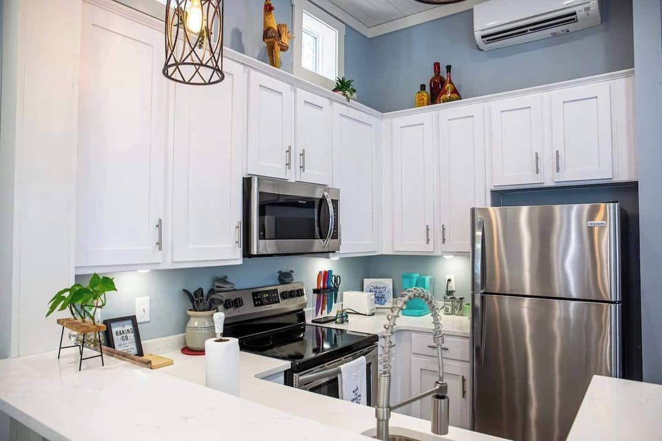 This modern kitchen combines style and function, featuring sleek white cabinetry, stainless steel appliances, and stylish decor.