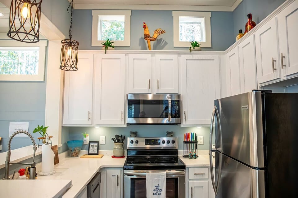 This kitchen exudes charm with its crisp white cabinets, stainless steel appliances, and unique decorative accents.