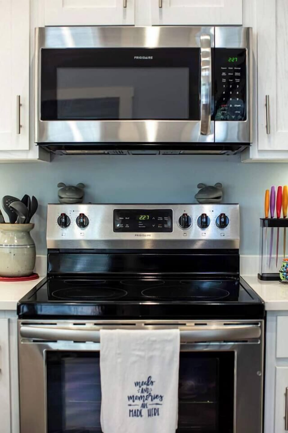 This modern kitchen setup features a sleek stainless steel stove and microwave, complemented by quirky frog figurines adding a playful touch