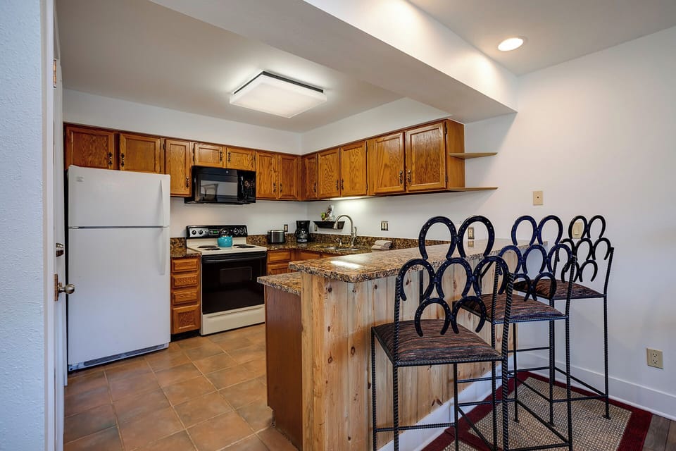 Your fully equipped kitchen features granite countertops, warm wood cabinetry, and a breakfast bar perfect for morning coffee or casual meals.