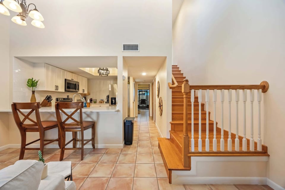 Open kitchen with breakfast bar seating and adjacent wooden staircase.