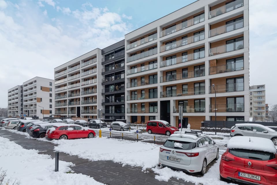An exterior view of the residential complex with modern architecture and parking spaces.

