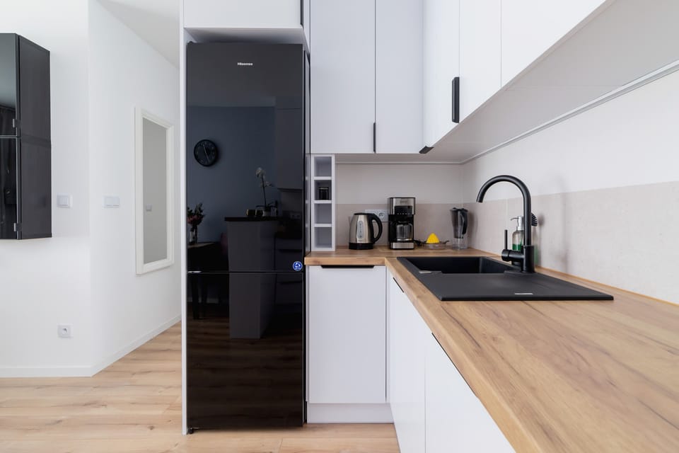 A kitchen corner with a black fridge, wooden surfaces, and efficient use of space.
