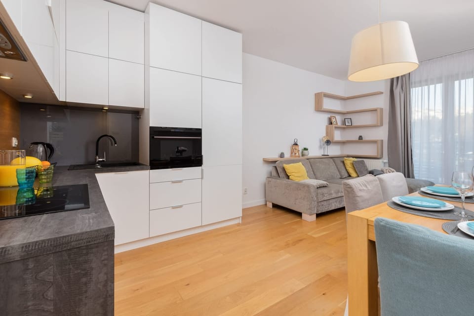 A kitchen view with white cabinets, wooden countertops, and a bright open-plan connection to the living area.
