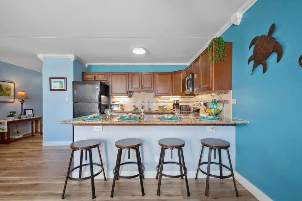 Fully equipped kitchen with full-size appliances, and dining area with 4 bar stools.