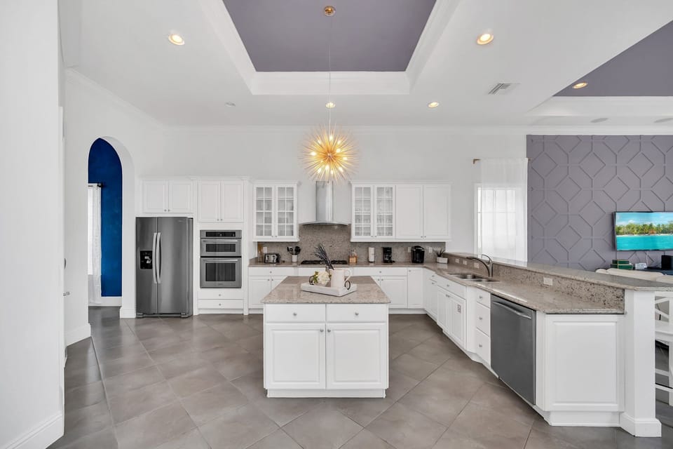 The open kitchen features modern appliances like a sleek 2-door fridge, oven, coffee maker, and more. With a central table at your disposal, meal preparation becomes a seamless and enjoyable experience.