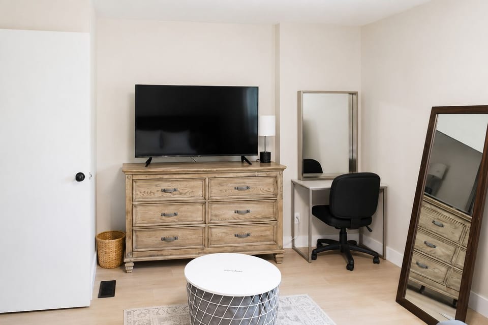 Your comfortable escape: primary bedroom with TV, pull-down couch, desk, soft carpet, dresser, closet, USB lamps, and cozy robes.