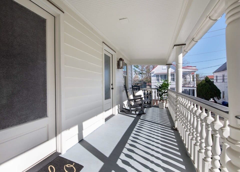 Relax on the private balcony featuring rocking chairs, comfortable lounge seating, and a coffee table for enjoying Charleston's fresh air.