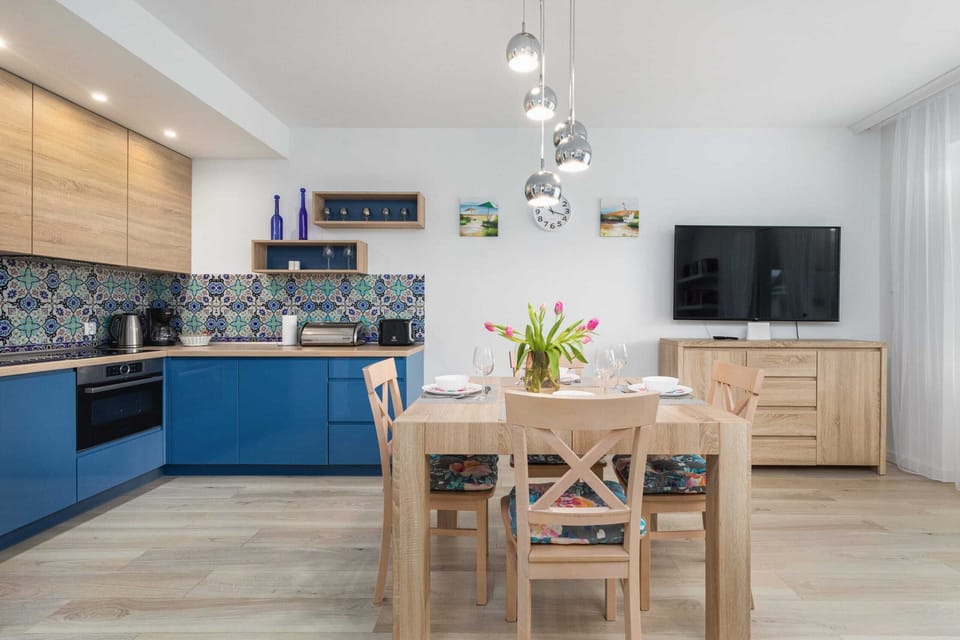 A modern kitchen with blue cabinetry, wooden countertops, and a dining area.
