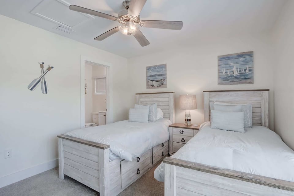The Second Bedroom Contains 2 Twin Beds, a Nightstand and Lamp, a Ceiling Fan and A En Suite Bathroom