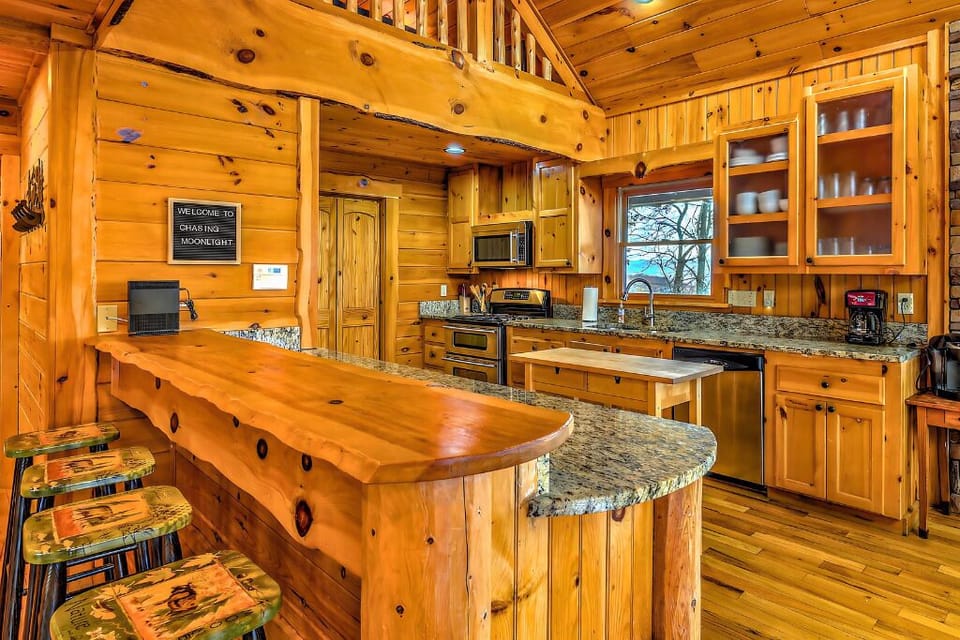 Stylish cabin kitchen with wood bar, granite counters, and stainless appliances!