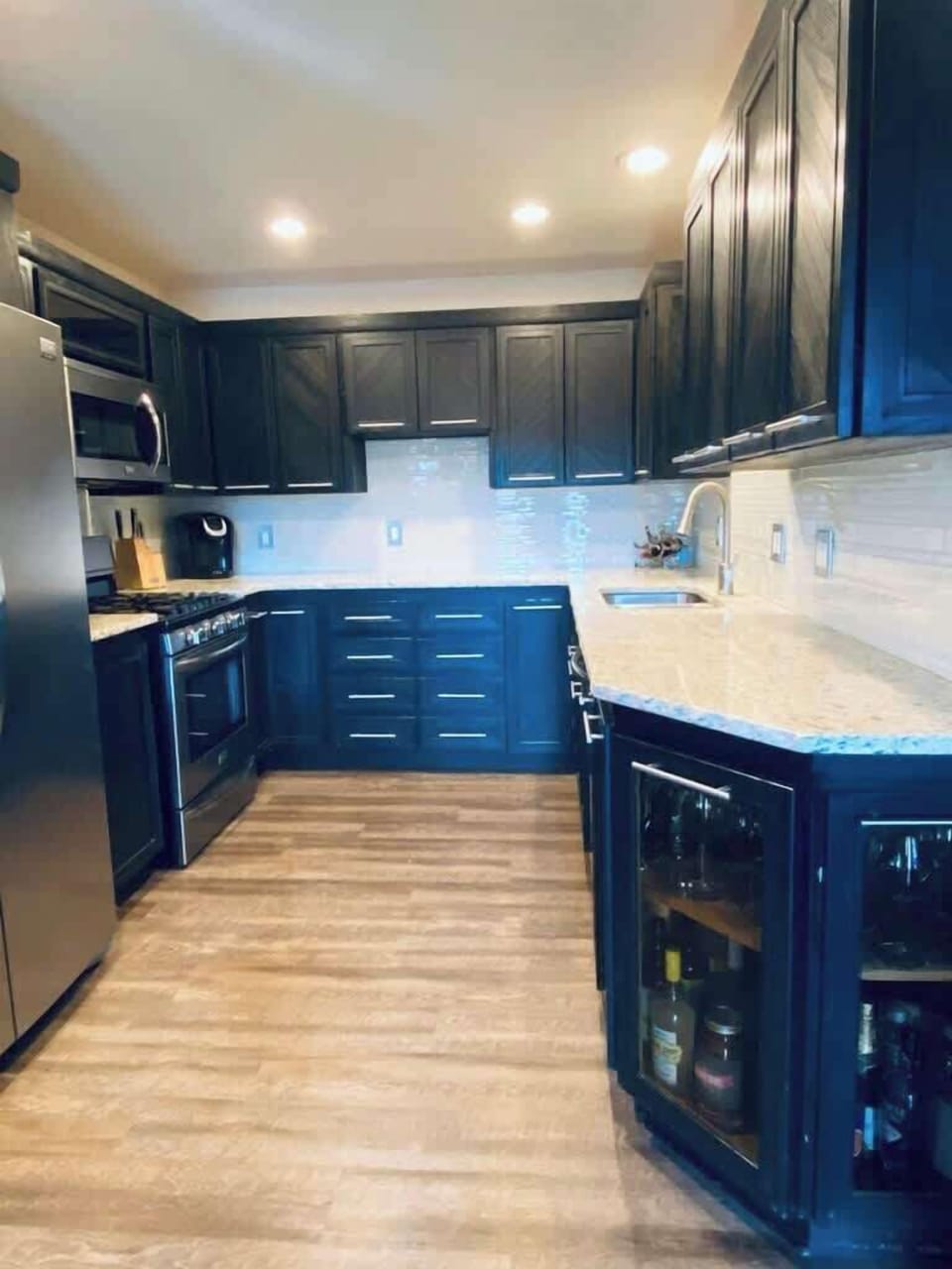 You will appreciate the sleek and modern kitchen, fully equipped with top-of-the-line appliances. The dark cabinetry and ample counter space make it perfect for preparing gourmet meals or casual snacks.