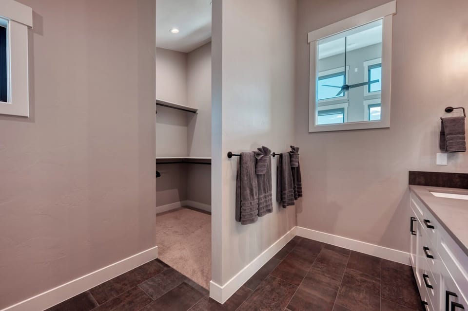 Spacious bathroom featuring a contemporary vanity, fresh towels, and an adjacent walk-in closet for your convenience.