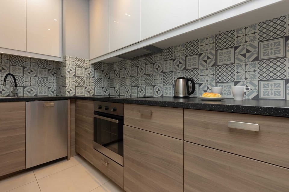 A detailed view of a fully equipped modern kitchen with patterned backsplash tiles.
