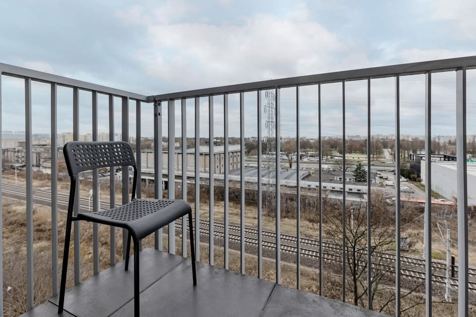 A view from the balcony with an outdoor chair overlooking a serene neighborhood.
