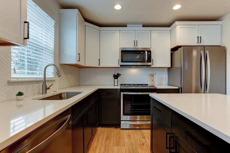 Stylish two-tone kitchen with quartz counters and full stainless suite