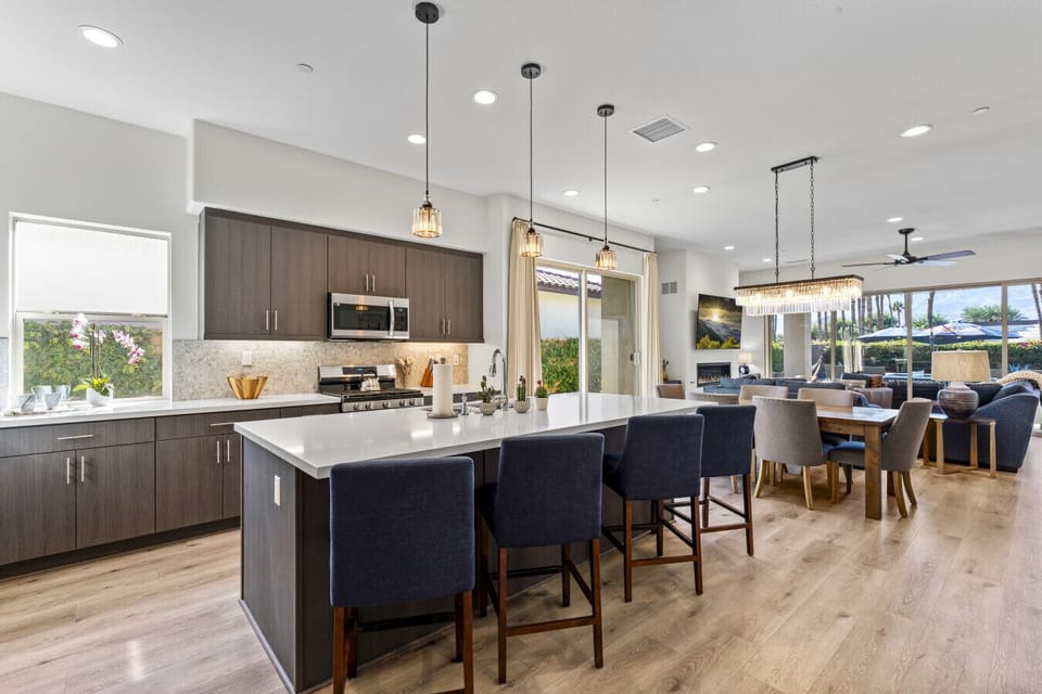 Modern kitchen w/ oversized island seating flowing into a bright open-concept living area