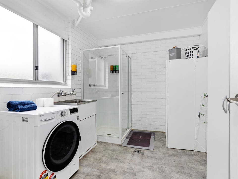 Main Bathroom Downstairs : This downstairs bathroom and laundry combines a shower, toilet and washing space for the lower level of Skye’s Beach House.