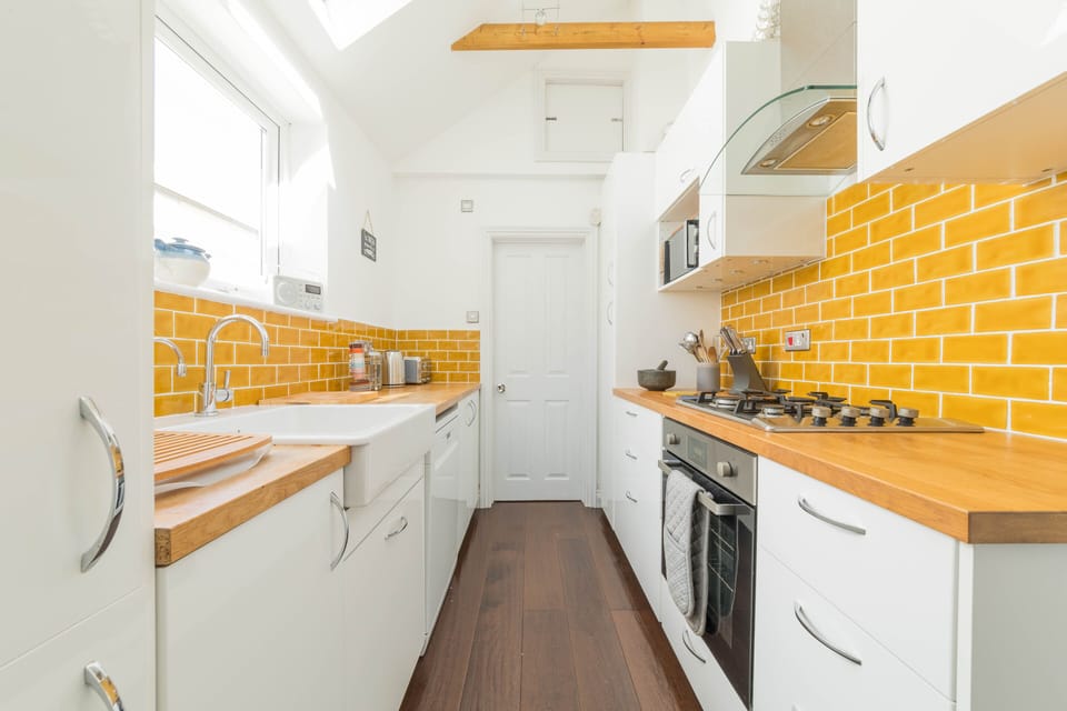 Fully equipped kitchen leading to downstairs bathroom and utility cupboard