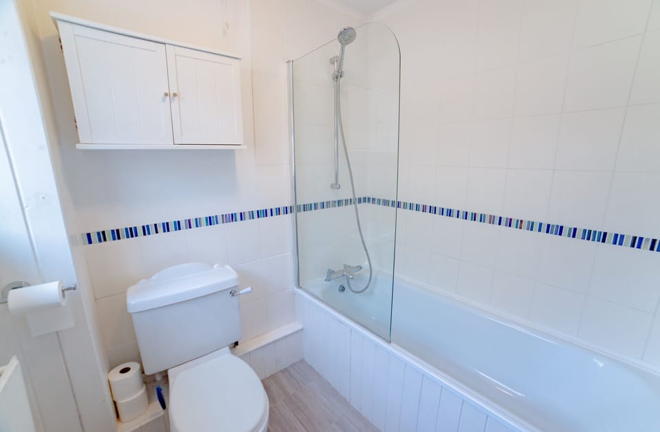 Ground floor bathroom with toilet, basin & shower over bath