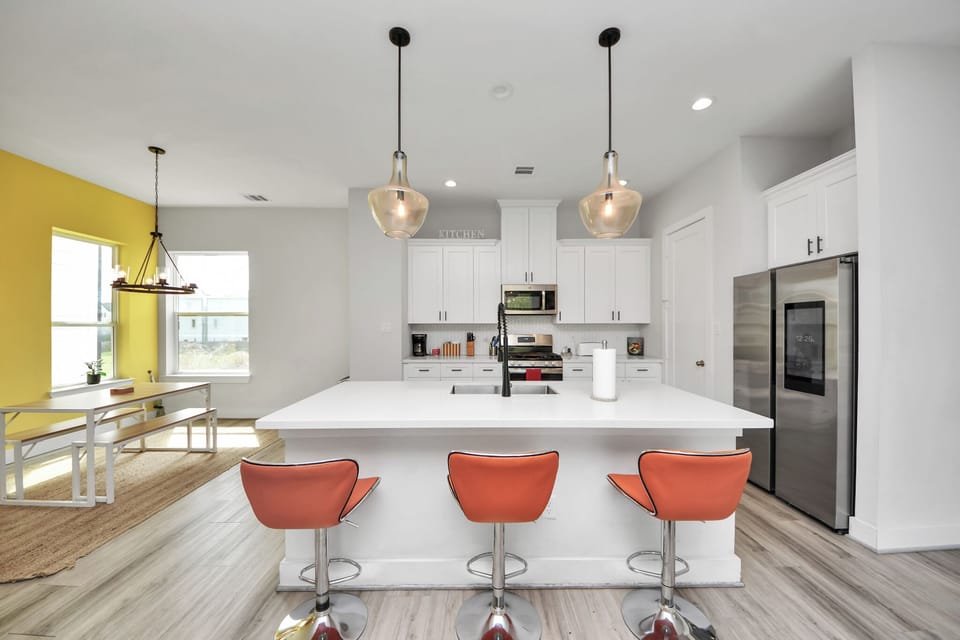 Lovely modern kitchen with marble countertops, stainless steel appliances, orang