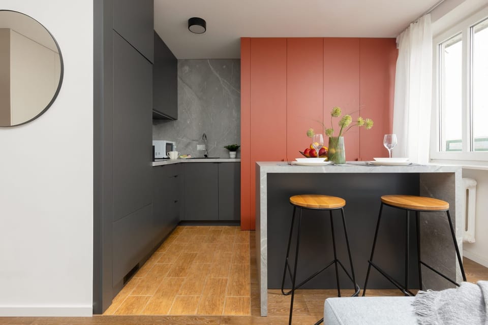 A sleek dining space featuring a black table, wooden stools, and red accent walls.
