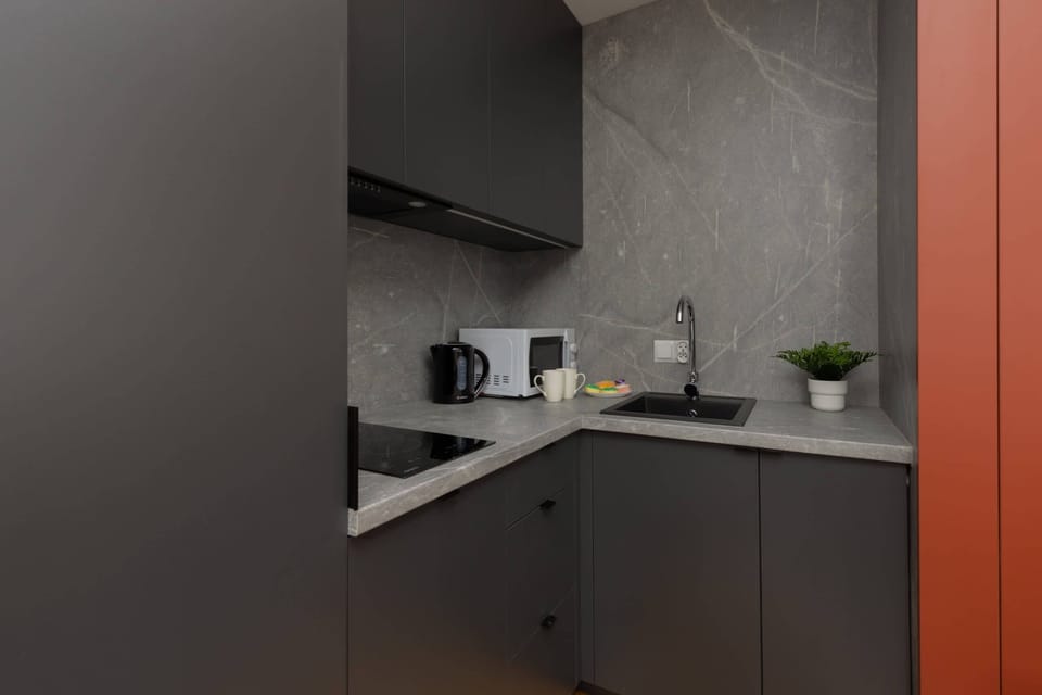 A close-up of a modern kitchen corner, showcasing sleek cabinets and a tiled backsplash.
