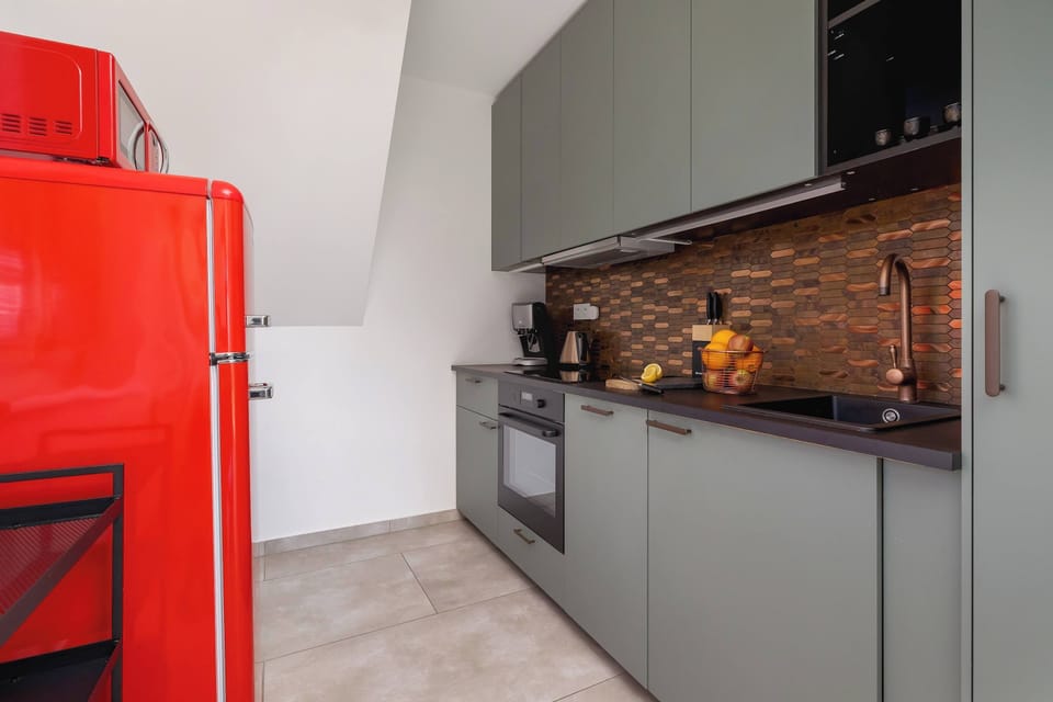 A modern kitchen with a striking red retro-style refrigerator and grey cabinetry.