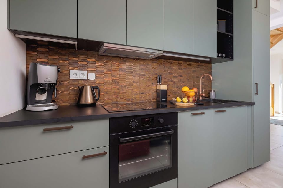 A modern kitchen with sleek cabinets, a stove, and a brick-style backsplash.