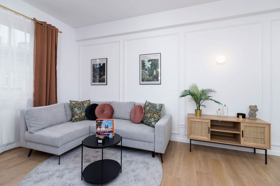 A bright and elegant living room with a modern gray sofa and wooden flooring.
