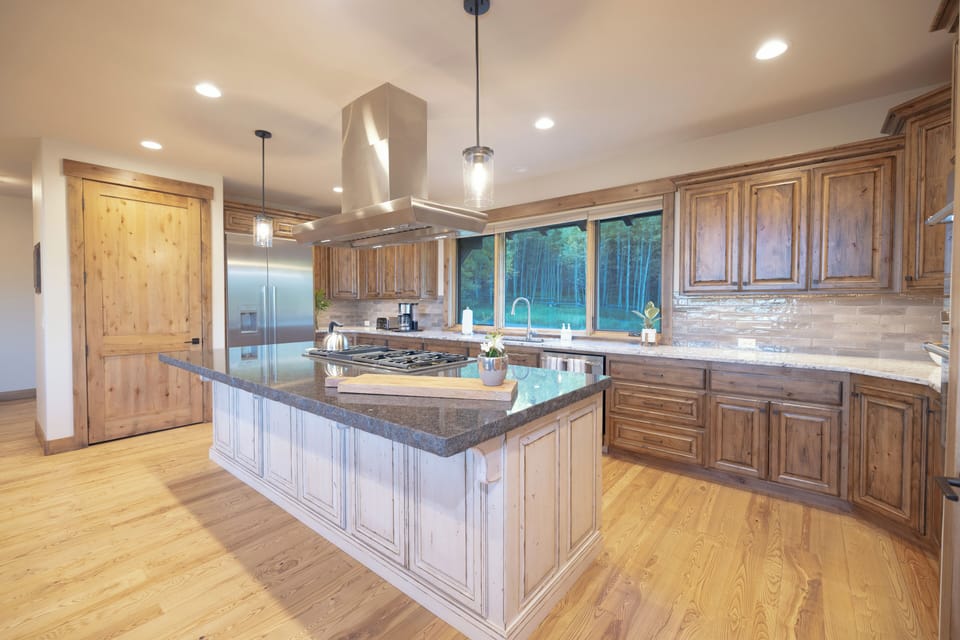 Step into your spacious gourmet kitchen where rich wood cabinets and gleaming granite invite you to create memorable meals. The large island becomes your gathering spot while forest views through the windows.