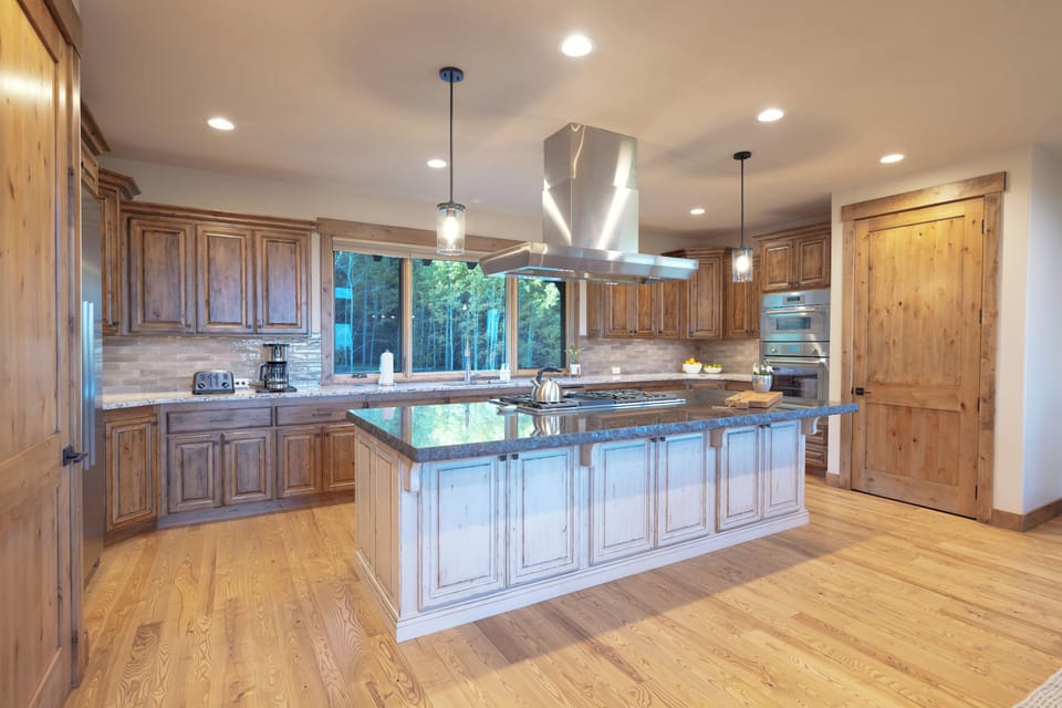 Your dream culinary haven awaits with rich wood cabinetry, granite countertops, and a spacious island perfect for gathering. Natural light streams through large windows, while modern appliances and pendant lighting create the perfect atmosphere.