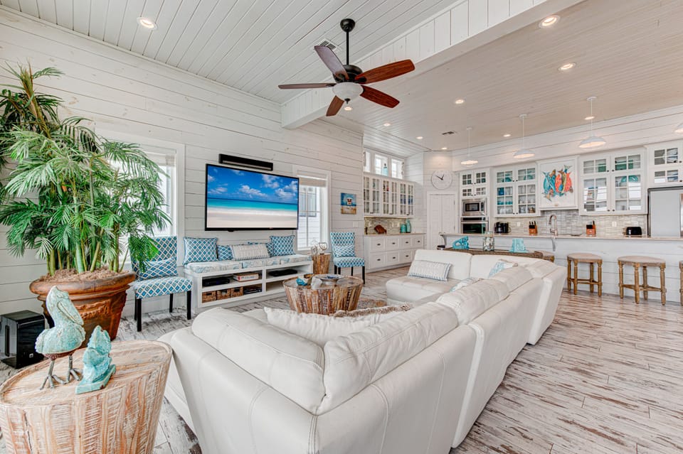 Sink into plush white sofas in this coastal-inspired great room, where shiplap walls and turquoise accents create your perfect beach house retreat.