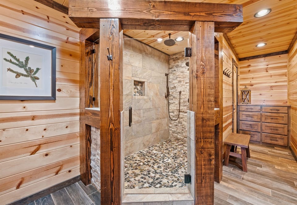 A spacious walk-in shower with natural stone walls and a pebble floor