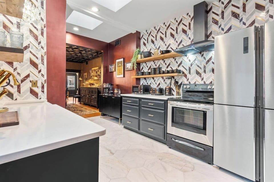A stunning chef-inspired kitchen featuring bold Prohibition-era styling, rich red walls, and dramatic patterned tile—perfect for cooking or entertaining in style.