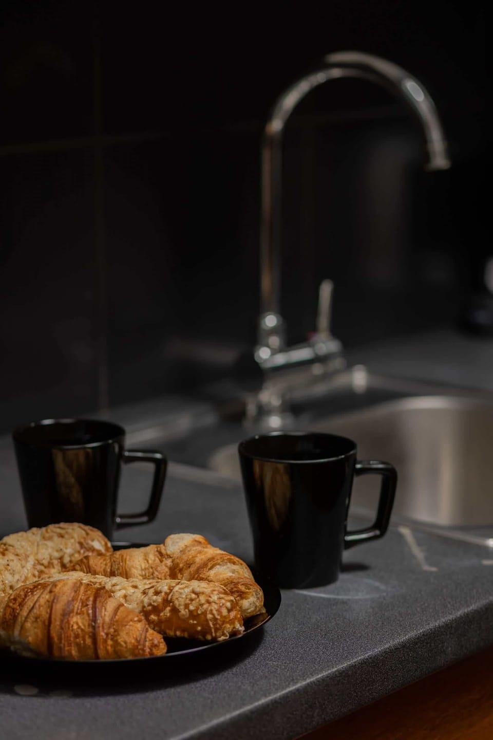A close-up of a kitchen counter with freshly baked croissants and coffee, creating a cozy atmosphere.





