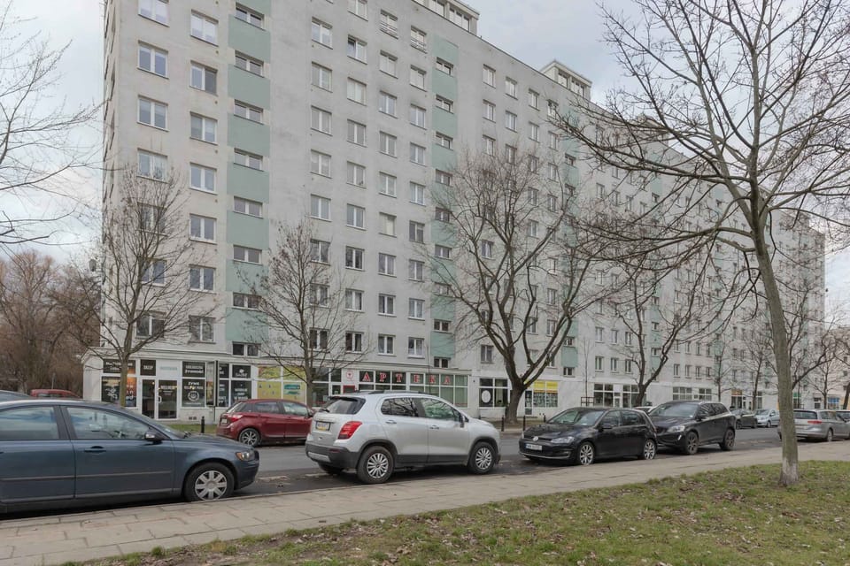 An exterior view of the building, surrounded by trees and parking spaces.
