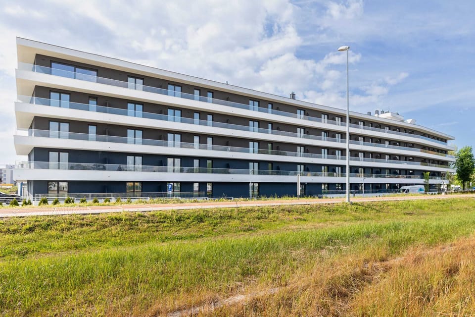 Exterior view of a modern building with wide green lawns in the foreground.
