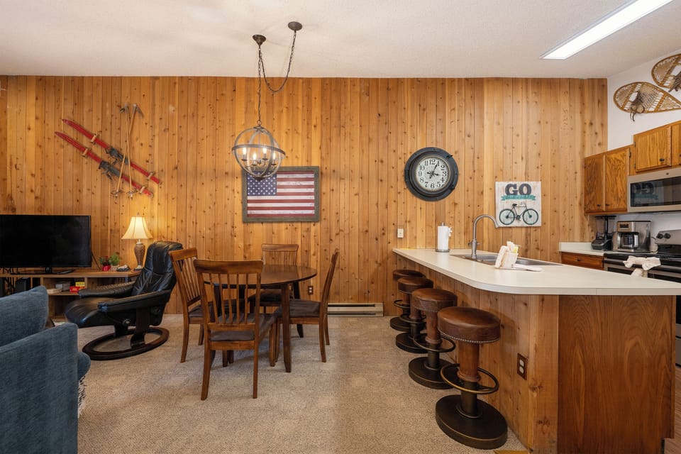 Cozy up in this rustic open-concept space featuring warm wood paneling, full kitchen, and comfortable seating perfect for your mountain getaway.