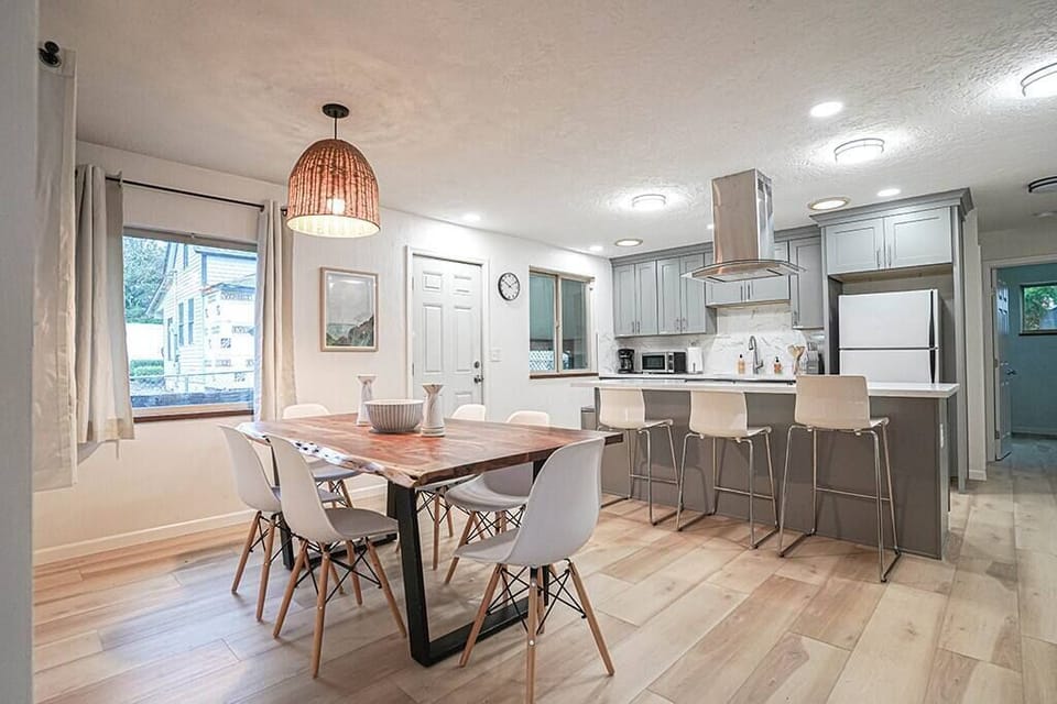 The heart of the home is the open and airy living space, with a fully-equipped kitchen complete with stainless-steel appliances, a large island with bar seating, a dining table that seats 6, and a comfortable living area